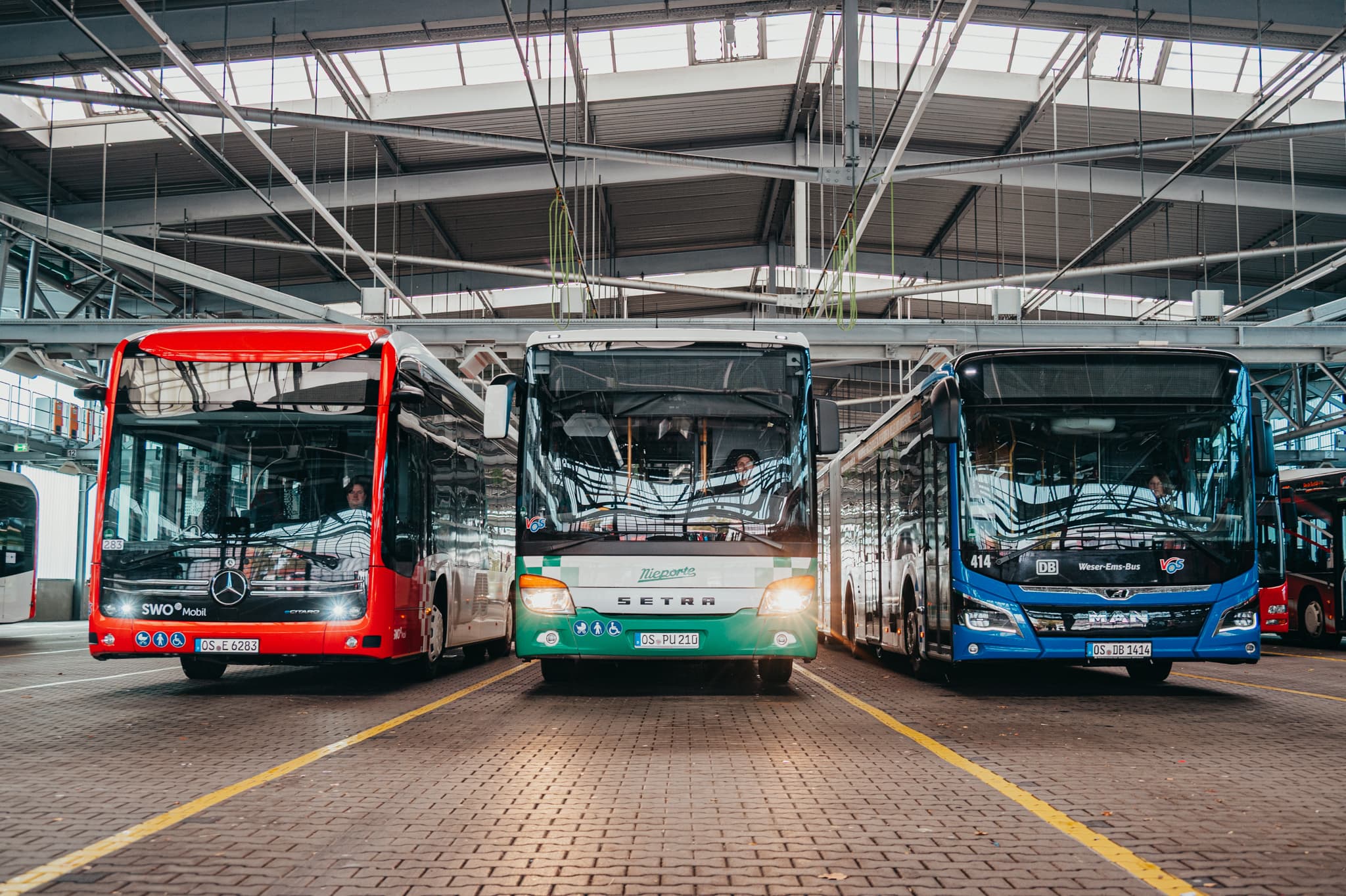 Linienbusse nebeneinander in der Fahrzeughalle des Betriebshofs