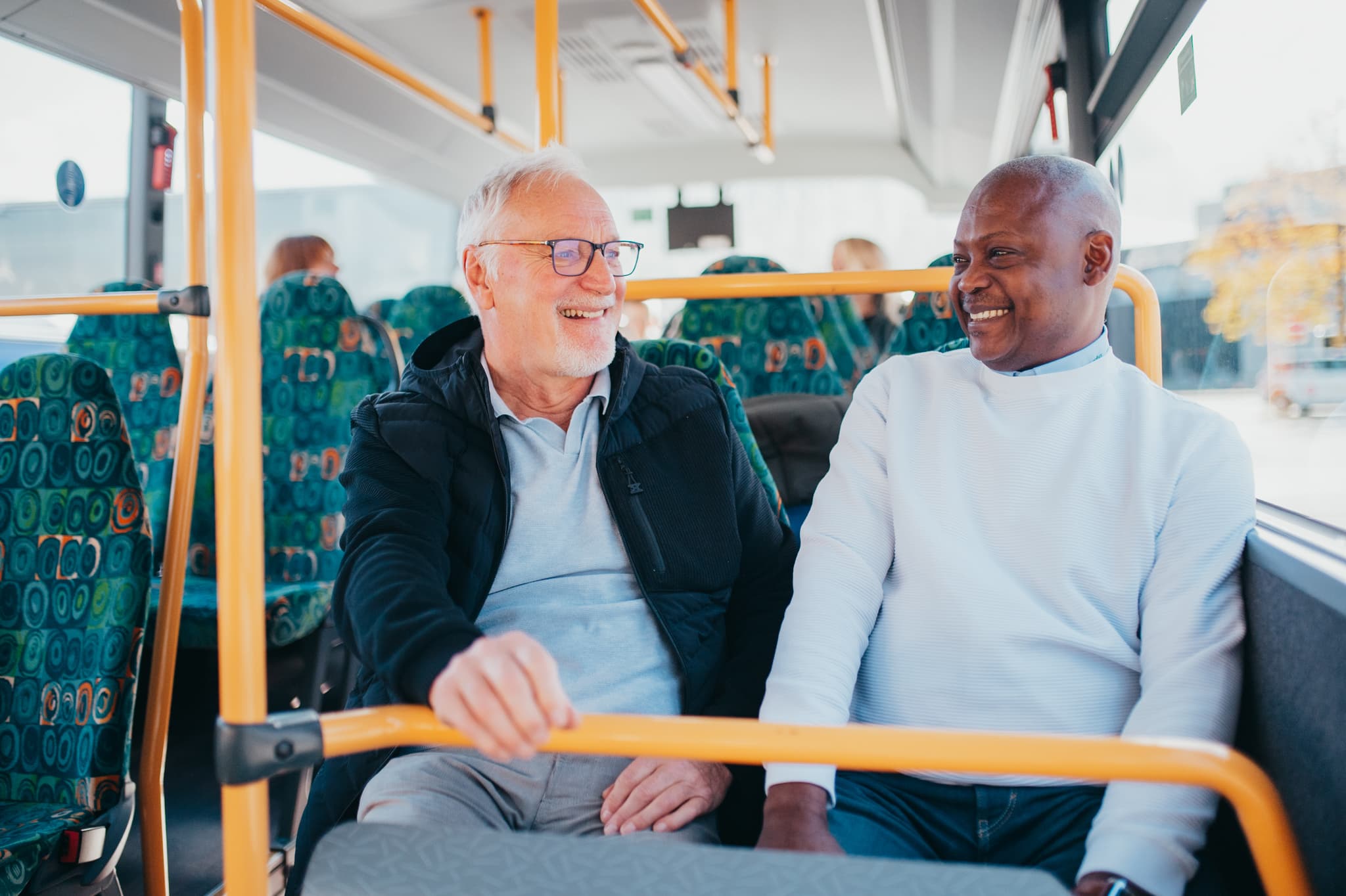 Ältere Fahrgäste sitzen im Innenraum eines Linienbusses